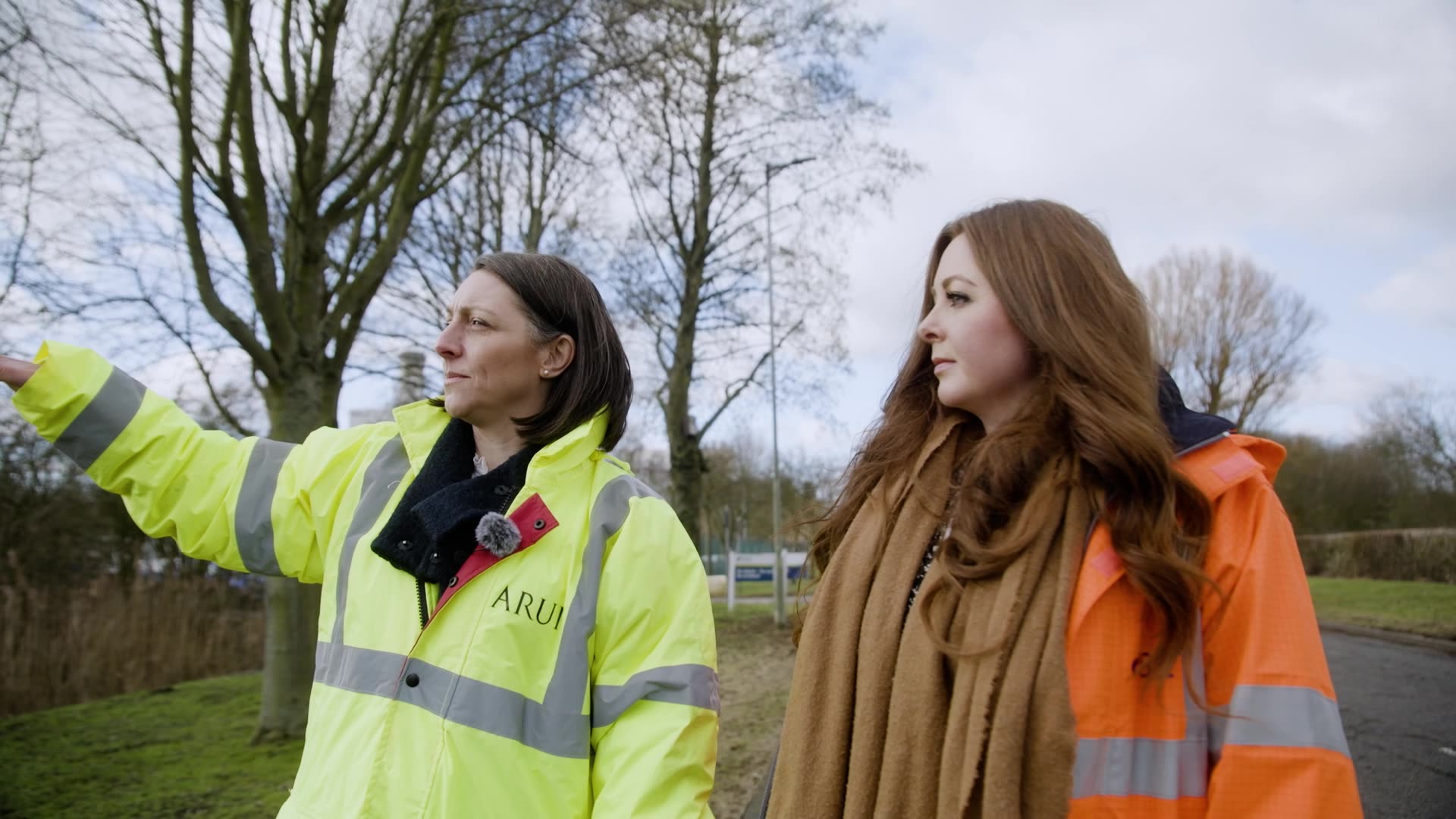 Two people walking through an industrial site and talking