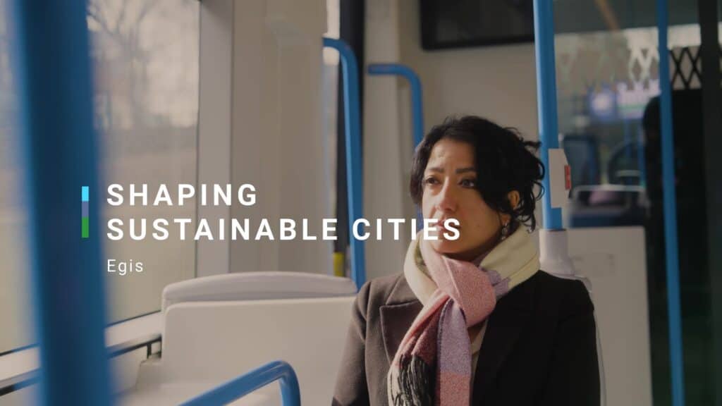 woman sat on a bus, still photo from Egis video. title across the screen - shaping sustainable cities