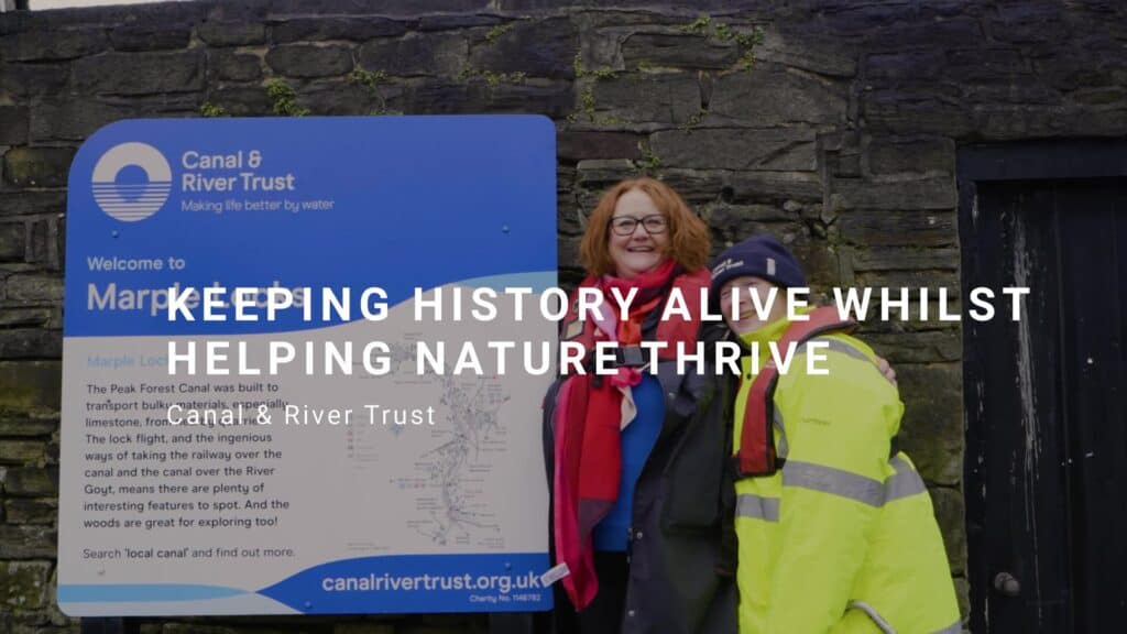 Two people smiling next to a Canal & River Trust sign. title reads: Keeping history alive whilst helping nature thrive