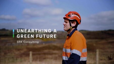 Photo of a man looking over a scene - wearing an orange high-vis top and a hard hat. Title reads: Unearthing a green future