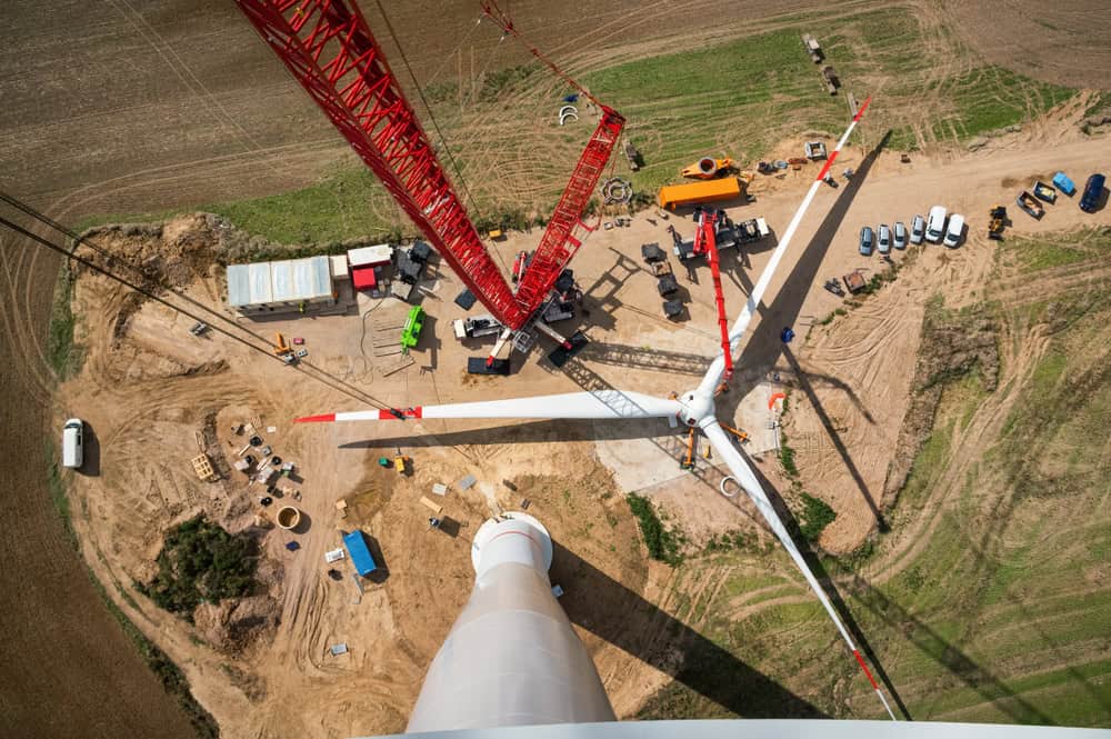 Aerial shot of a wind turbine blade on the ground, with lots of construction work happening