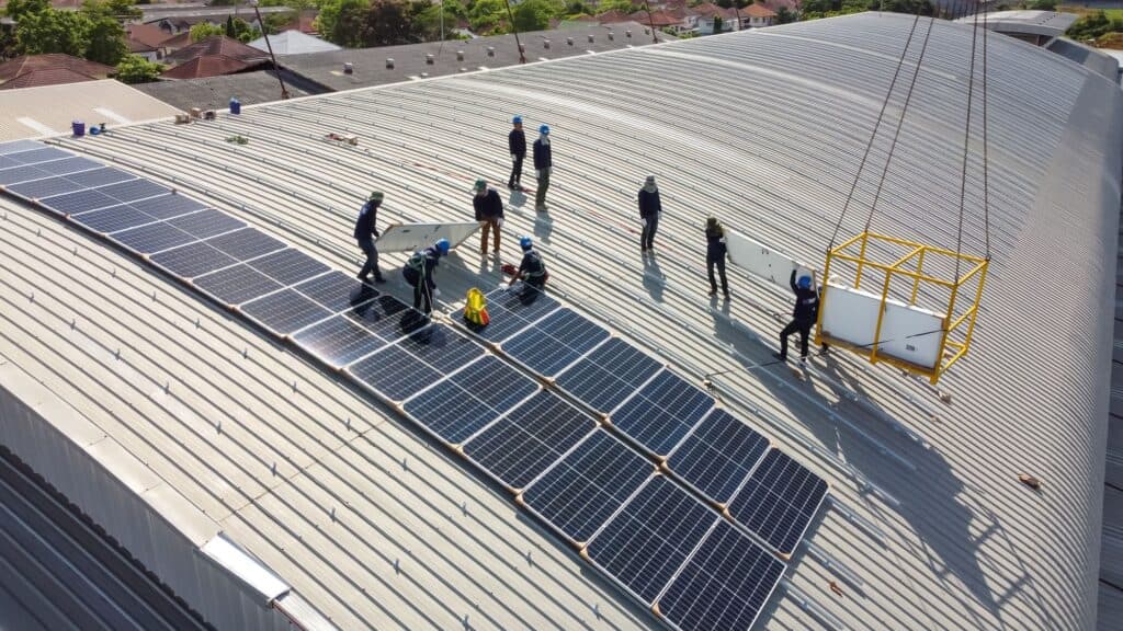 People installing solar panels on top of a large warehouse