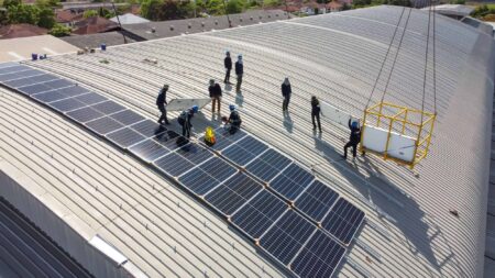 People installing solar panels on top of a large warehouse