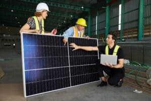 Three people looking at a solar panel in a building