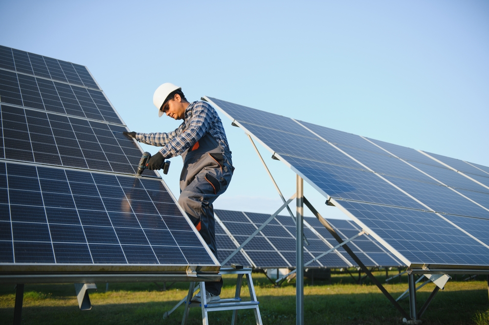 Man working on a large solar panel in a field