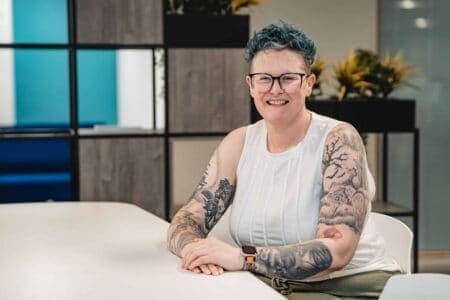 Picture of Heidi Barnard sat down at a table looking and smiling at the camera