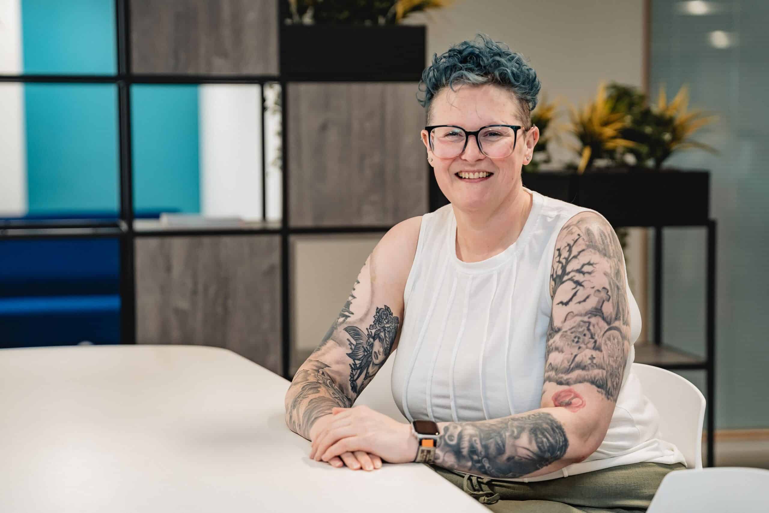 Picture of Heidi Barnard sat down at a table looking and smiling at the camera