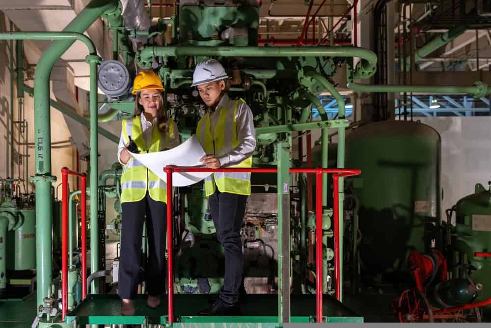 A picture of two people looking at a piece of paper inside a power station