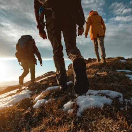 Photo of the lower half of three people walking along a ridge