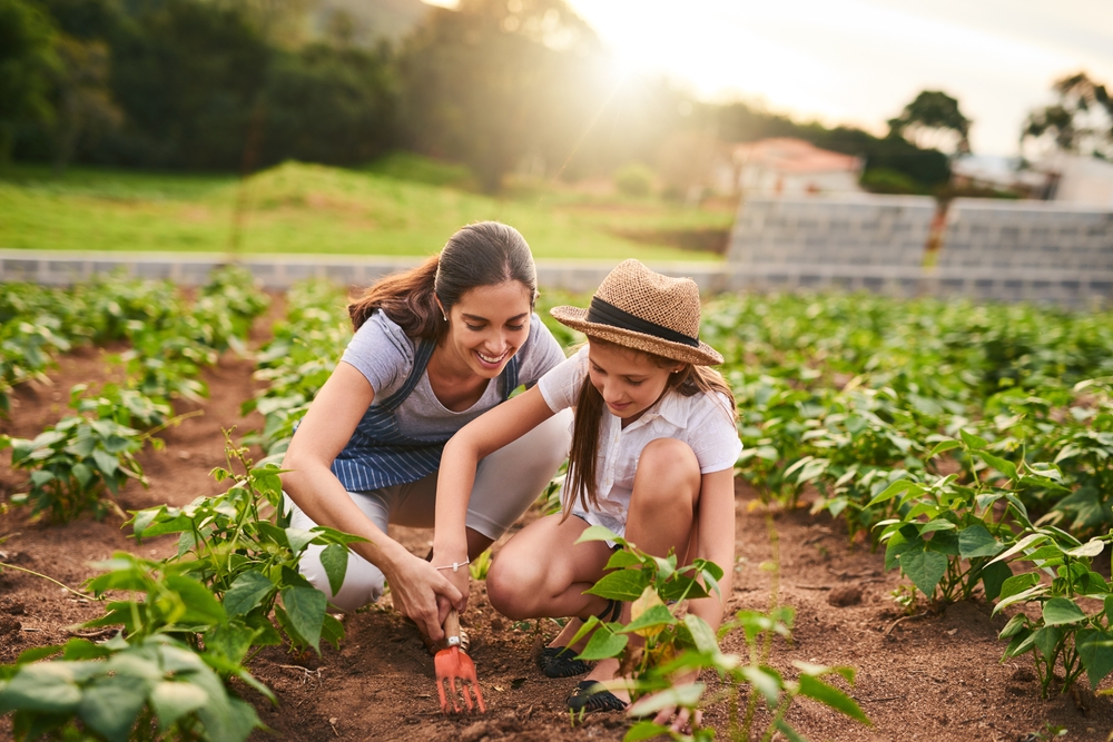 A woman teaching a young girl gardening at a farm in the countryside