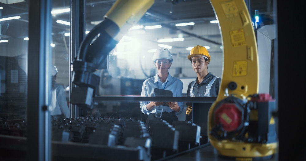Photo of two engineers in a factory looking at some machinery